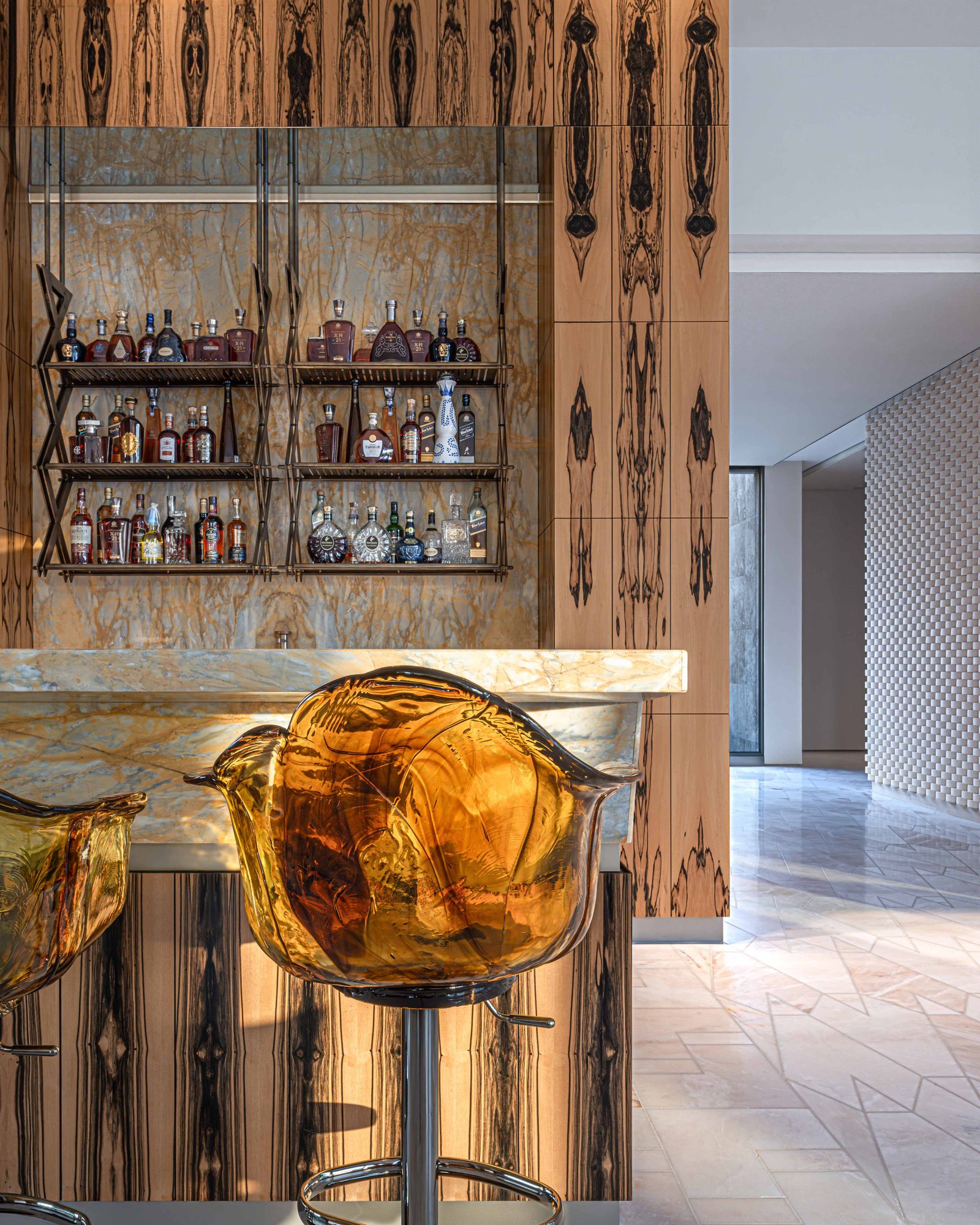 A bar wall clad in book-matched white ebony veneer beside a marble counter